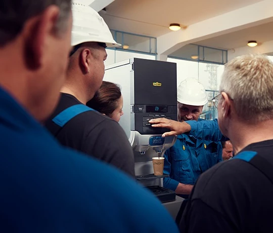 Eine Gruppe Arbeiter bedient gerade eine Jacobs Professional Cafitesse Quantum 110 Kaffeemaschine.