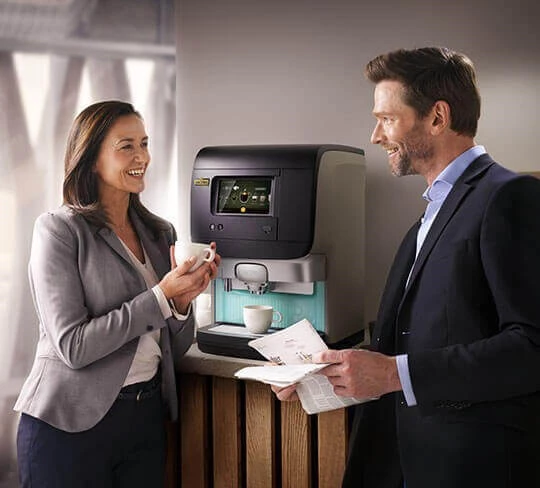 Zwei Kollegen trinken eine Tasse Kaffee aus der Jacobs Professional Cafitesse Kaffeemaschine