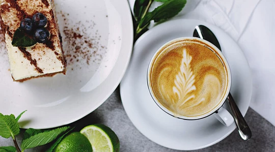 Abbildung einer Tasse Kaffee mit einem Stück Kuchen.