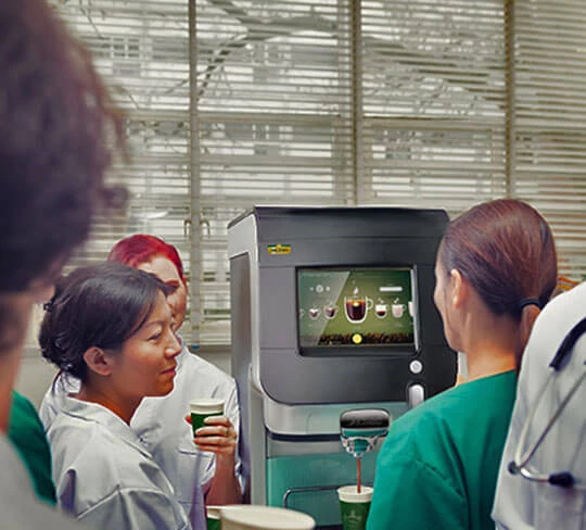 Eine Cafitesse Excellence Touch Kaffeemaschine wird gerade von einer Mitarbeiterin im Health & Care Bereich bedient.