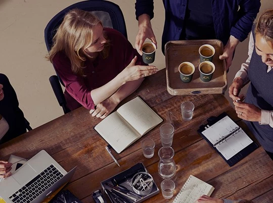 Mitarbeiter im Büro sitzen am Tisch und trinken Kaffee von Jacobs Professional