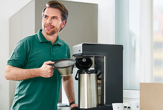 Ein Mann reinigt gerade eine Filtermaschine von Jacobs Professional