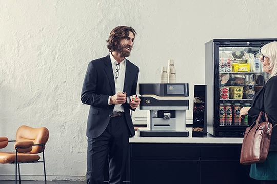 Eine Frau und ein Mann unterhalten sich bei einer Tasse Jacobs Professional Kaffee auf der Arbeit