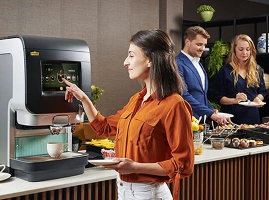 Eine Frau holt sich Kaffee von der Jacobs Cafitesse auf der Arbeit