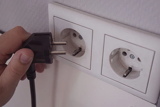 Der Stecker der Cafitesse Excellence Compact Touch wird gezogen.