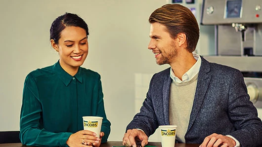 Eine Frau und ein Mann trinken Kaffee von Jacobs Professional