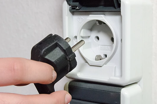 Der Stromstecker der Promesso Kaffeemaschine wird gerade herausgezogen