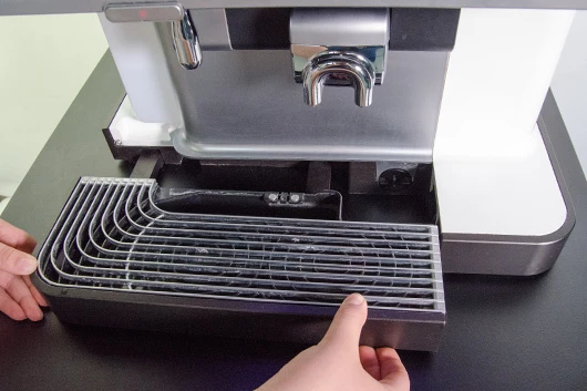 Die Tropfschale der Promesso Kaffeemaschine von Jacobs Professional wird entfernt.