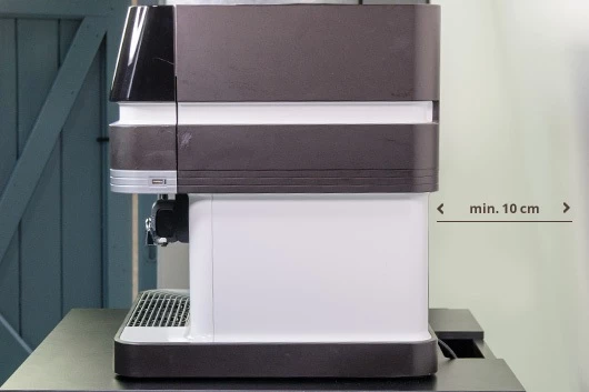 Der Abstand der Promesso Kaffeemaschine von Jacobs Profesisonal zur Wand wird geprüft.